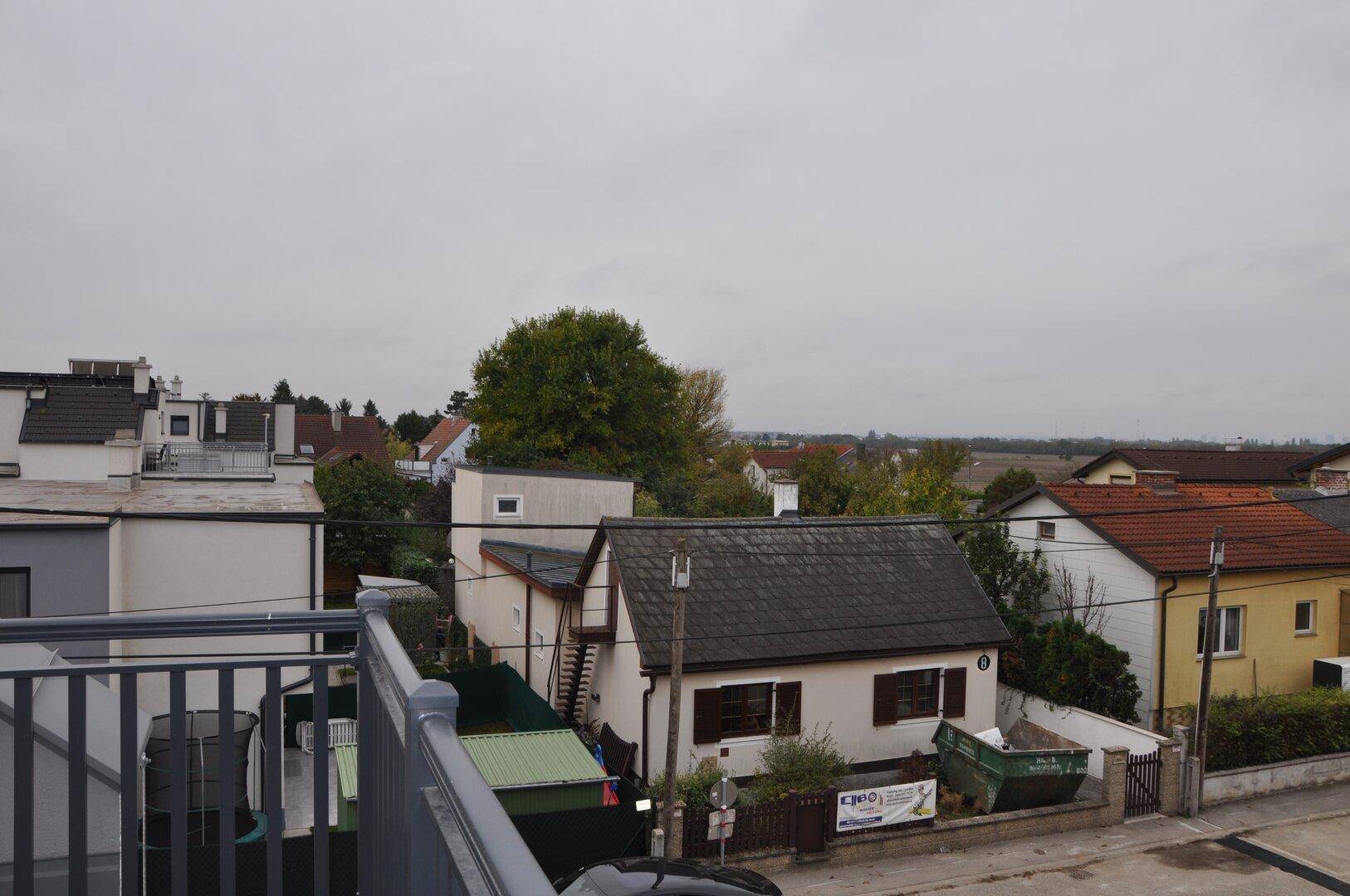 Weitblick über die Dächer der Nachbarschaft und die umliegende Landschaft unter grauem Himmel.