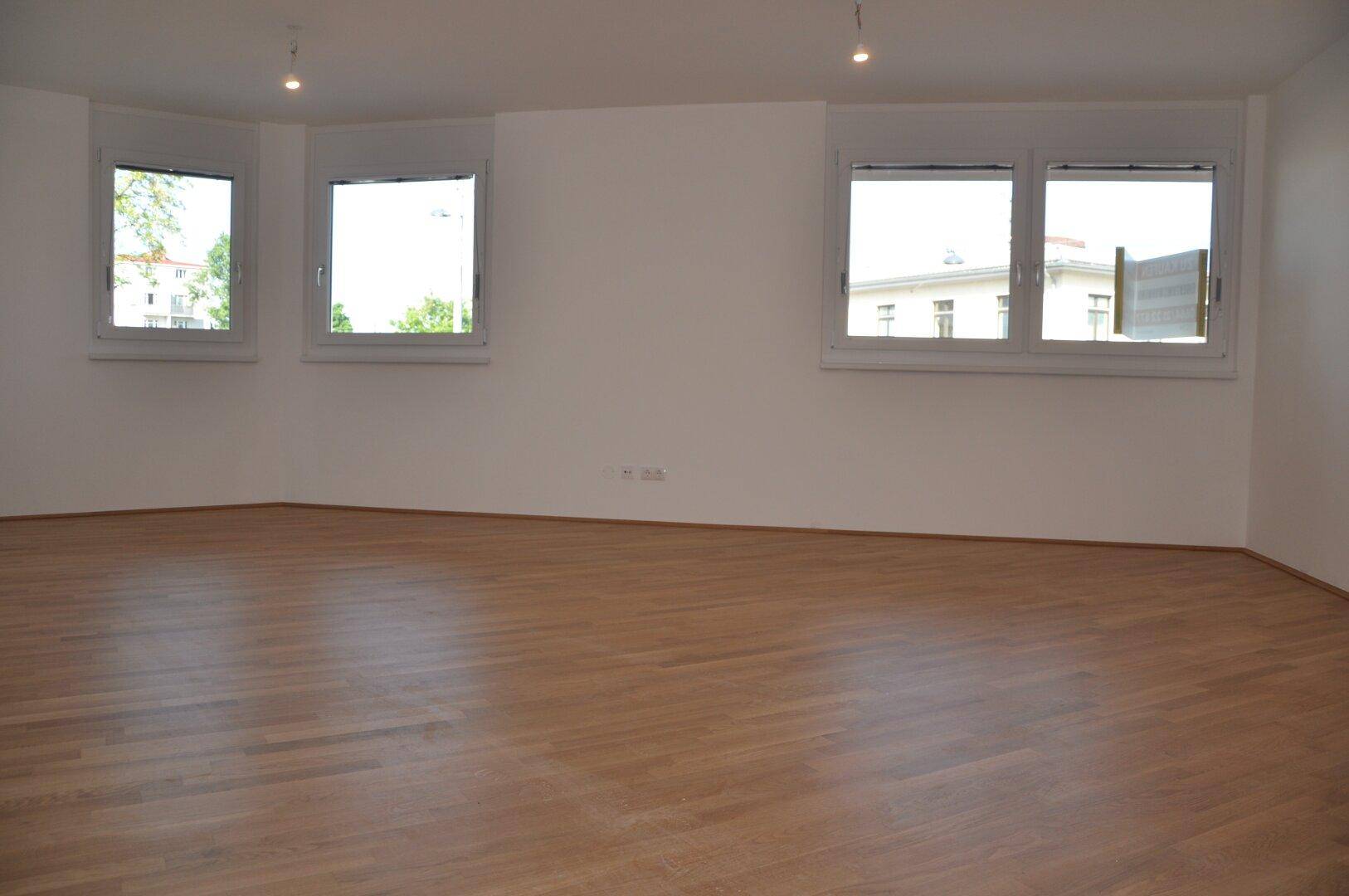 Heller, leerer Raum mit Parkettboden und großen Fenstern, bereit zur individuellen Gestaltung.