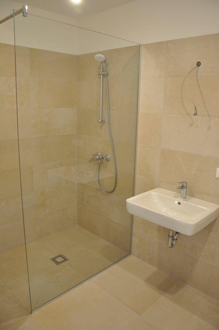 Modernes Badezimmer mit begehbarer Dusche und eleganten beigefarbenen Fliesen.