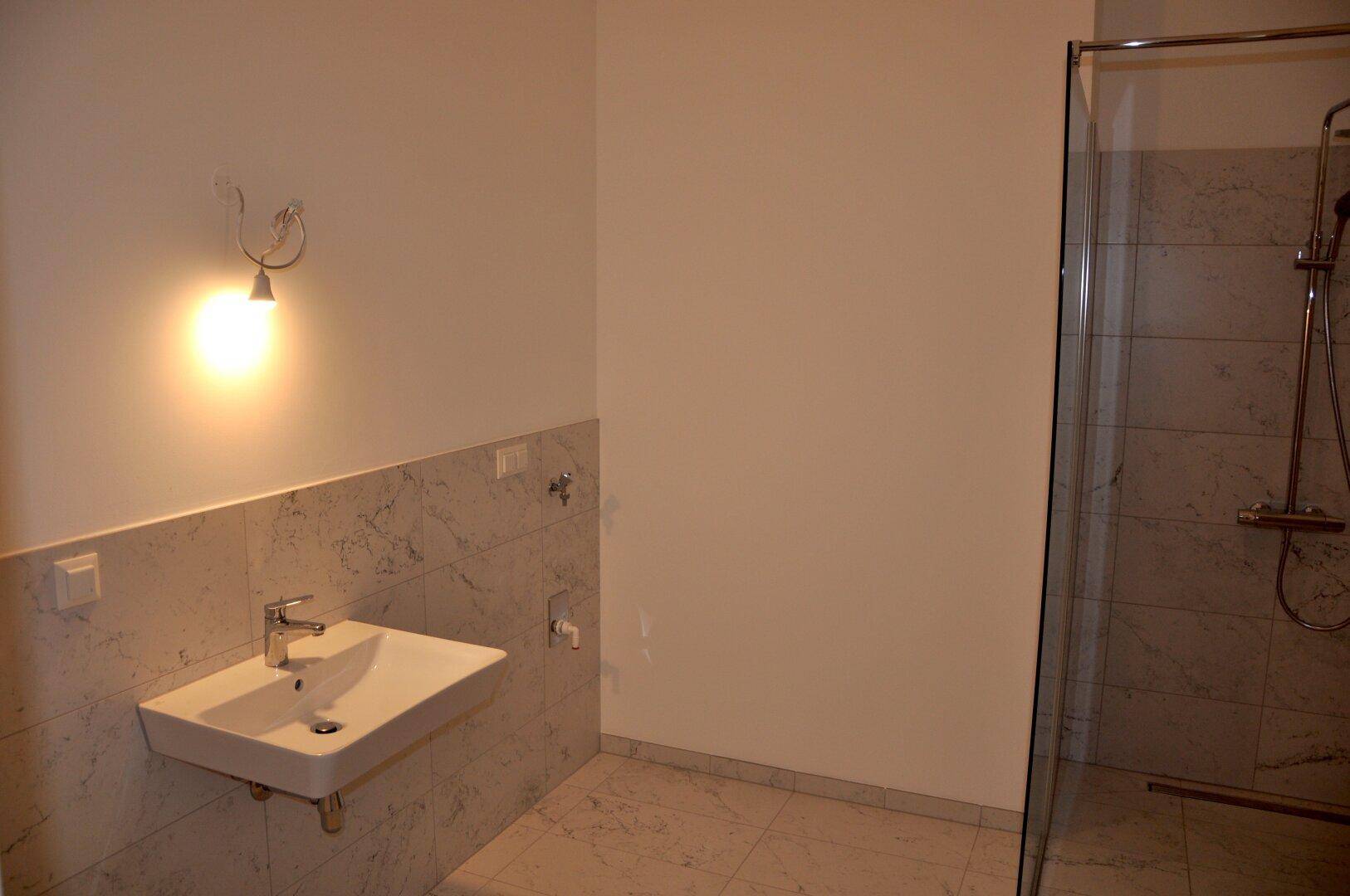 Badezimmer mit modernem Waschbecken, gefliesten Wänden und einer geräumigen Dusche.