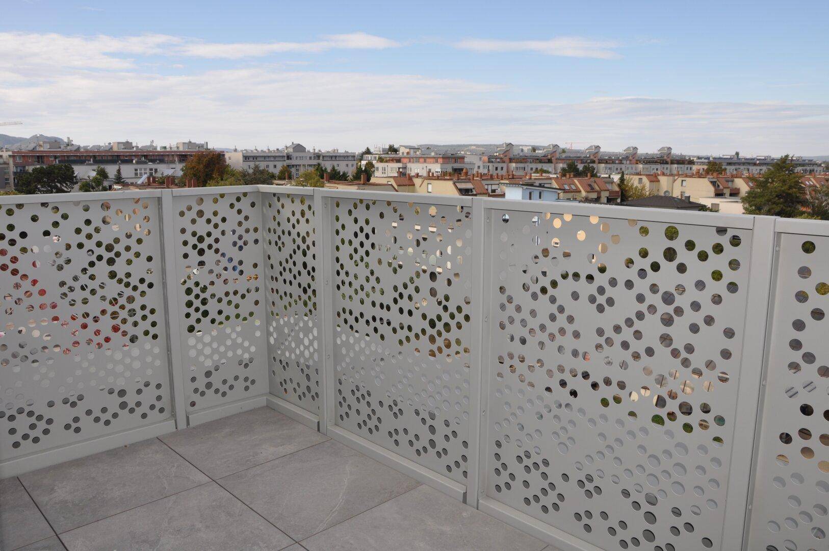 Weitläufige Terrasse mit modernem Design und Blick auf die Stadtlandschaft unter blauem Himmel.