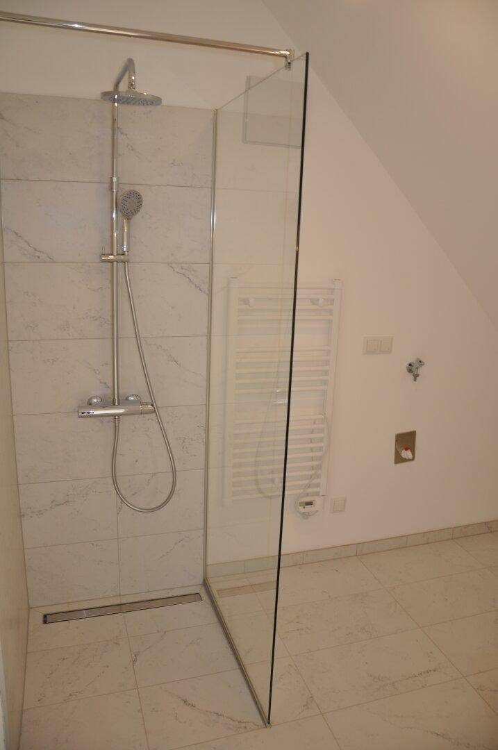 Modernes Badezimmer mit begehbarer Dusche, weißen Fliesen und beheiztem Handtuchhalter.