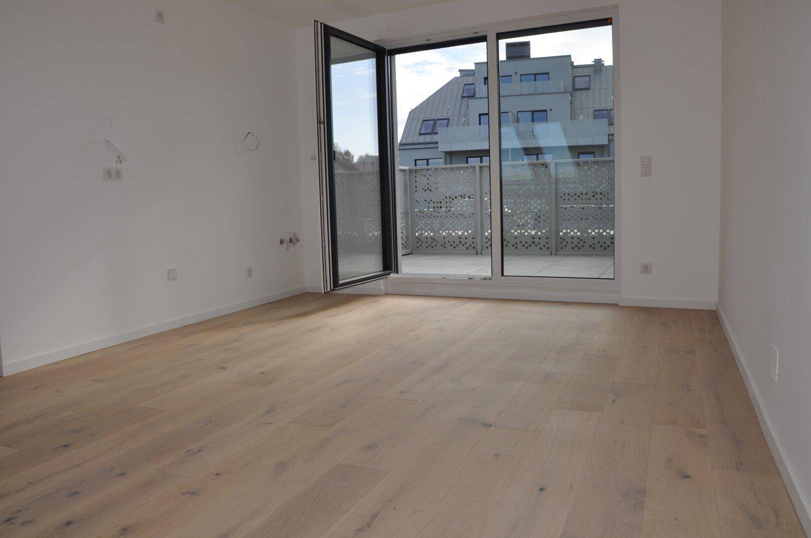 Heller Wohnraum mit Holzboden und Zugang zu einer großzügigen Terrasse mit Stadtblick.