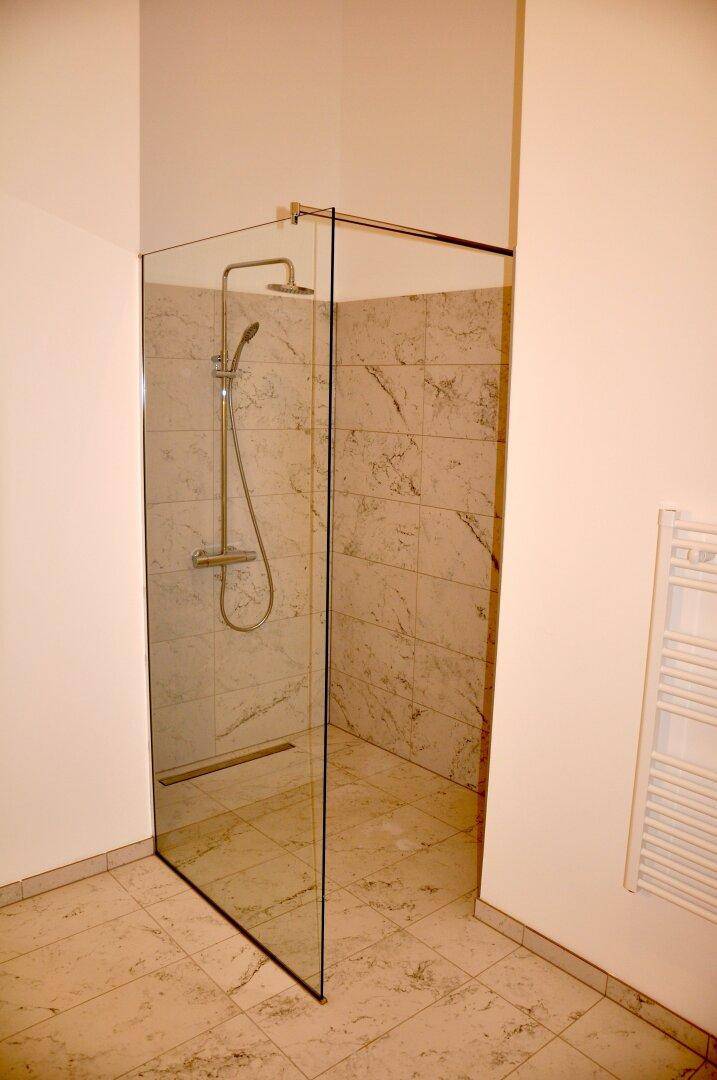 Modernes Badezimmer mit begehbarer Dusche, Fliesen und einem beheizten Handtuchhalter.