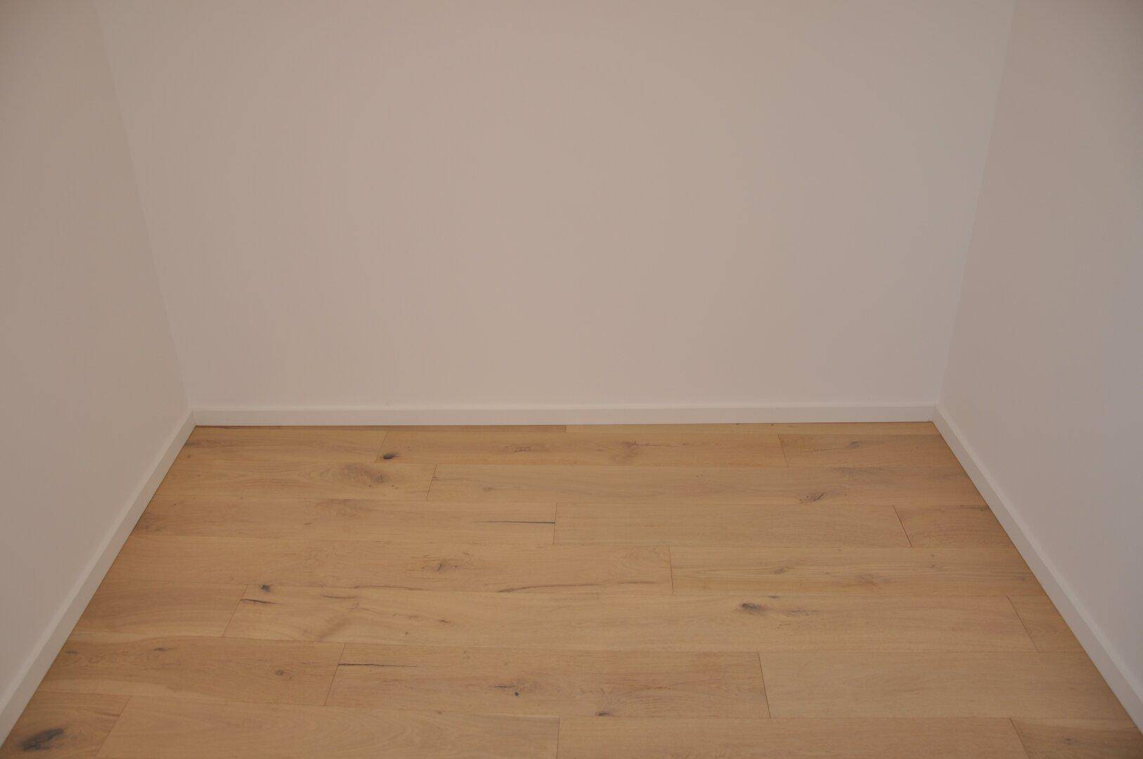 Kleiner, leerer Raum mit Holzboden, ideal als Abstellraum oder begehbarer Kleiderschrank.
