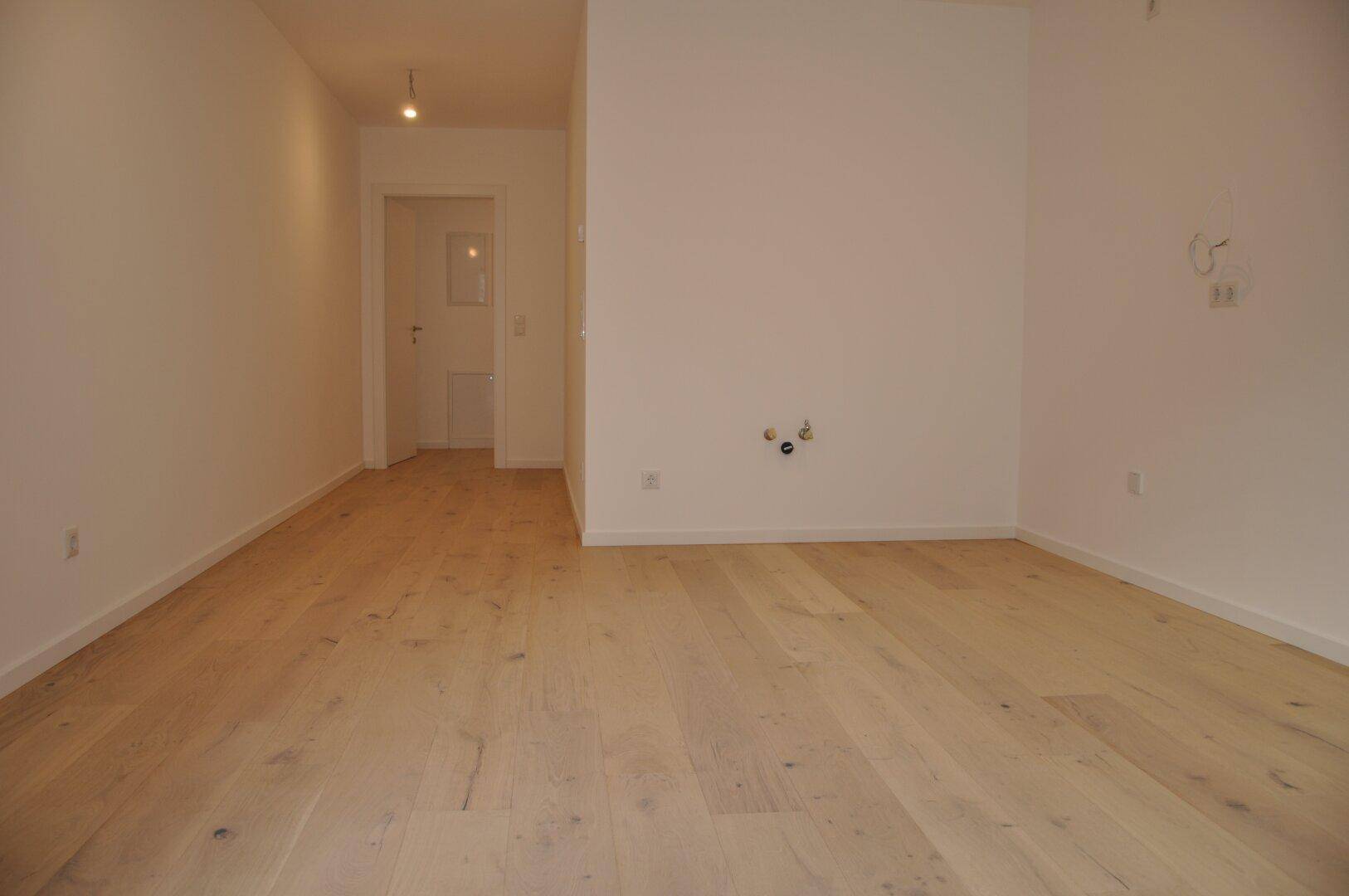 Heller Raum mit Holzboden und Anschlüssen an der Wand, vielseitig nutzbar.