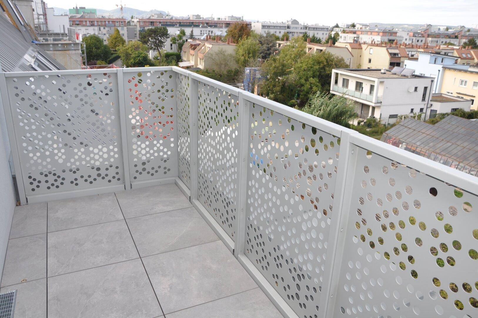 Weitläufige Terrasse mit perforiertem Geländer und Panoramablick über die städtische Umgebung.
