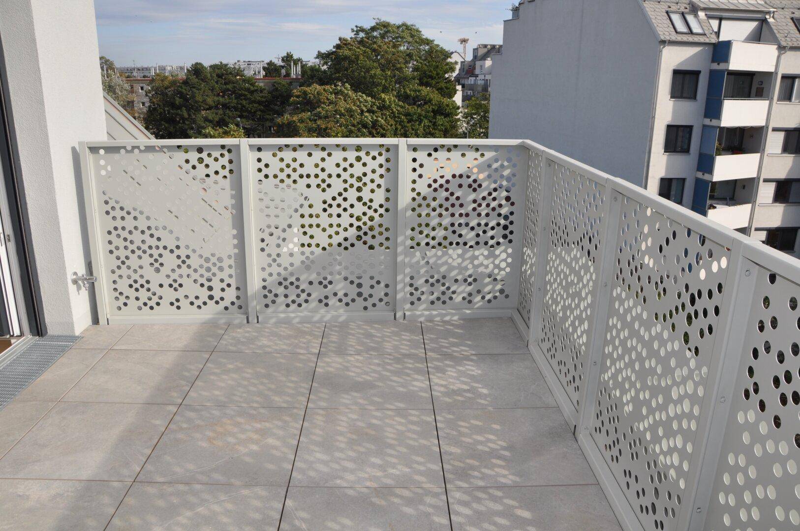 Geräumige Terrasse mit modernem Geländer und Fliesenboden, umgeben von städtischer Architektur.