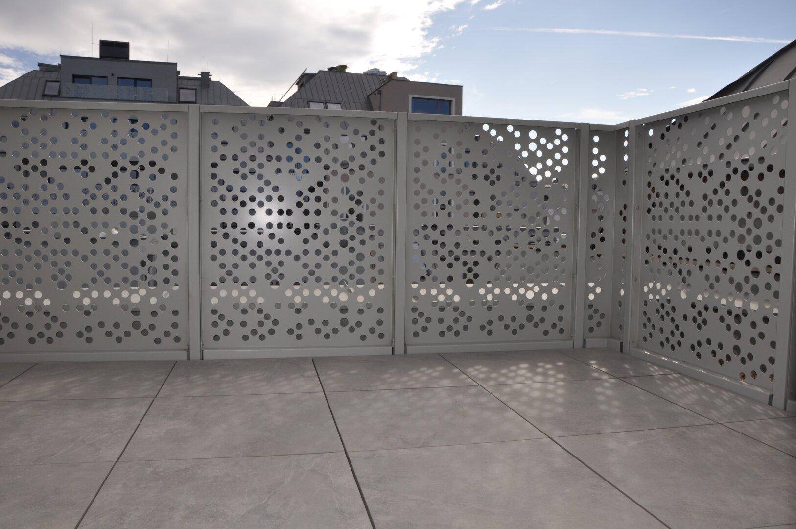 Große Terrasse mit modernem Lochblechgeländer und Fliesenboden, ideal für Entspannung.