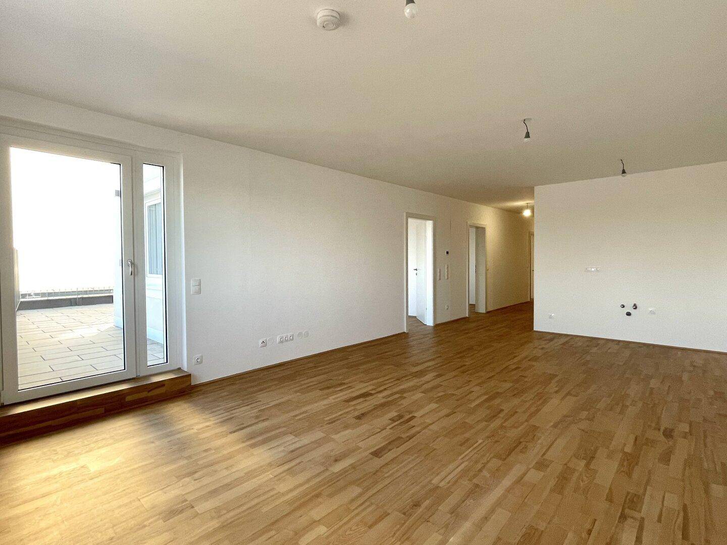 Helles Wohnzimmer mit hellem Parkettboden und direktem Zugang zu einer Außenterrasse.