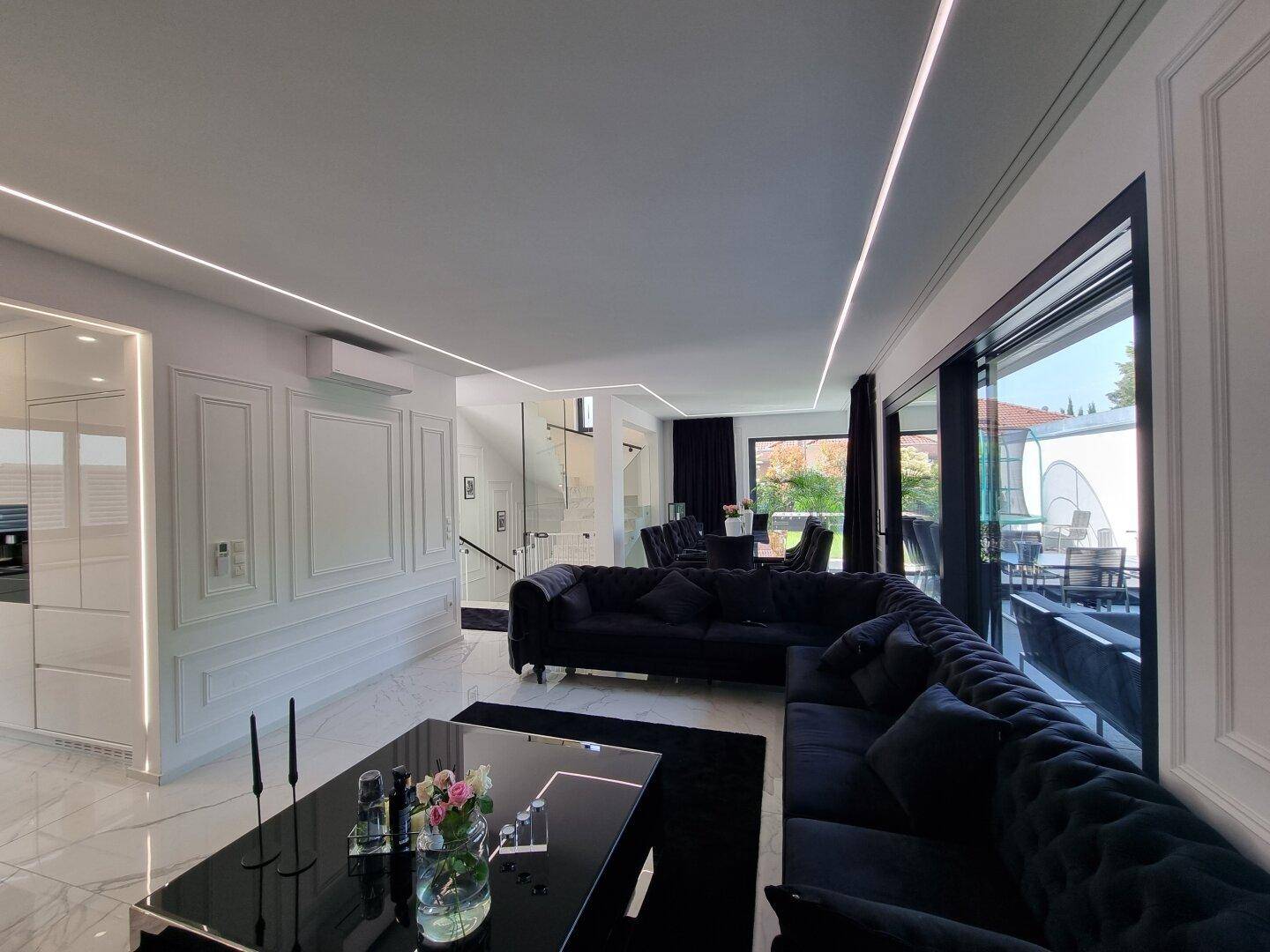 Heller, offener Wohnbereich mit elegantem Sofa, Essbereich und Zugang zur Terrasse.