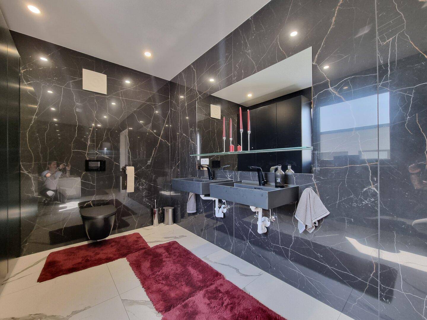 Luxuriöses Badezimmer mit schwarzen Marmorwänden, Doppelwaschbecken und moderner Toilette.
