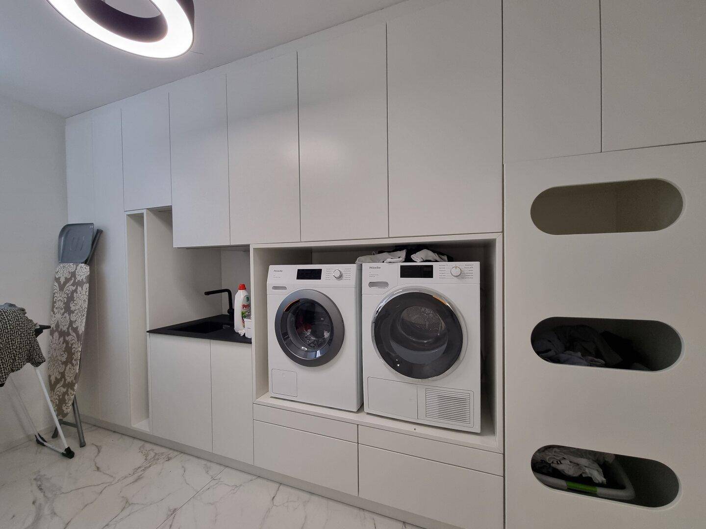Funktionaler Hauswirtschaftsraum mit Waschmaschine, Trockner und integrierten Schränken.