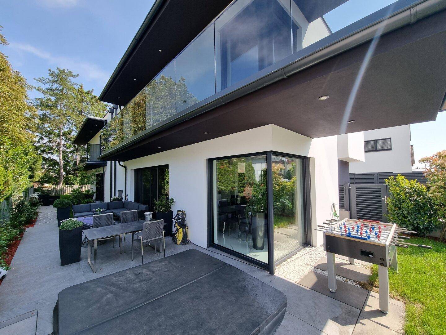 Geräumige Terrasse mit Essbereich im Freien, Whirlpool und Tischfußball neben der modernen Villa.