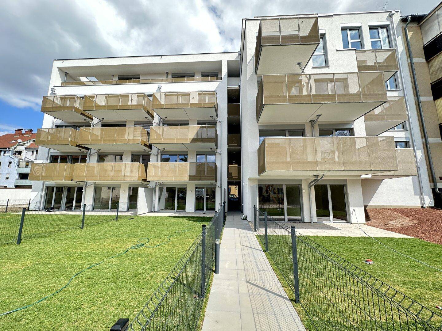 Zeitgemäßes Apartmentgebäude mit klarer Linienführung, Balkonen und einer grünen Außenanlage.