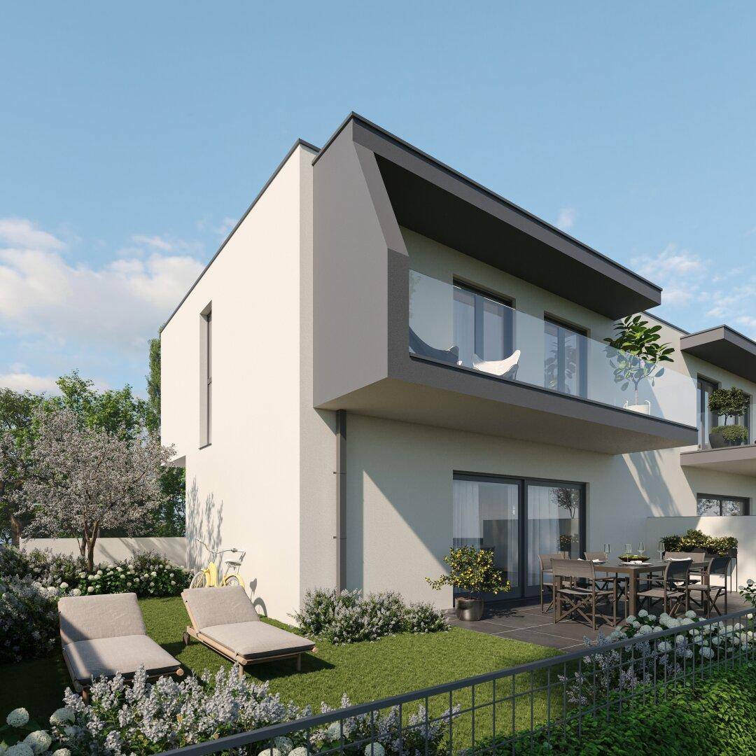 Seitlicher Blick auf ein modernes Reihenhaus mit möblierter Terrasse und kleinem Rasenbereich.