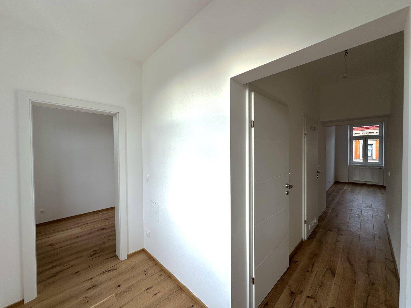 Heller Flur mit Holzboden und mehreren Türen, die zu verschiedenen Räumen führen.