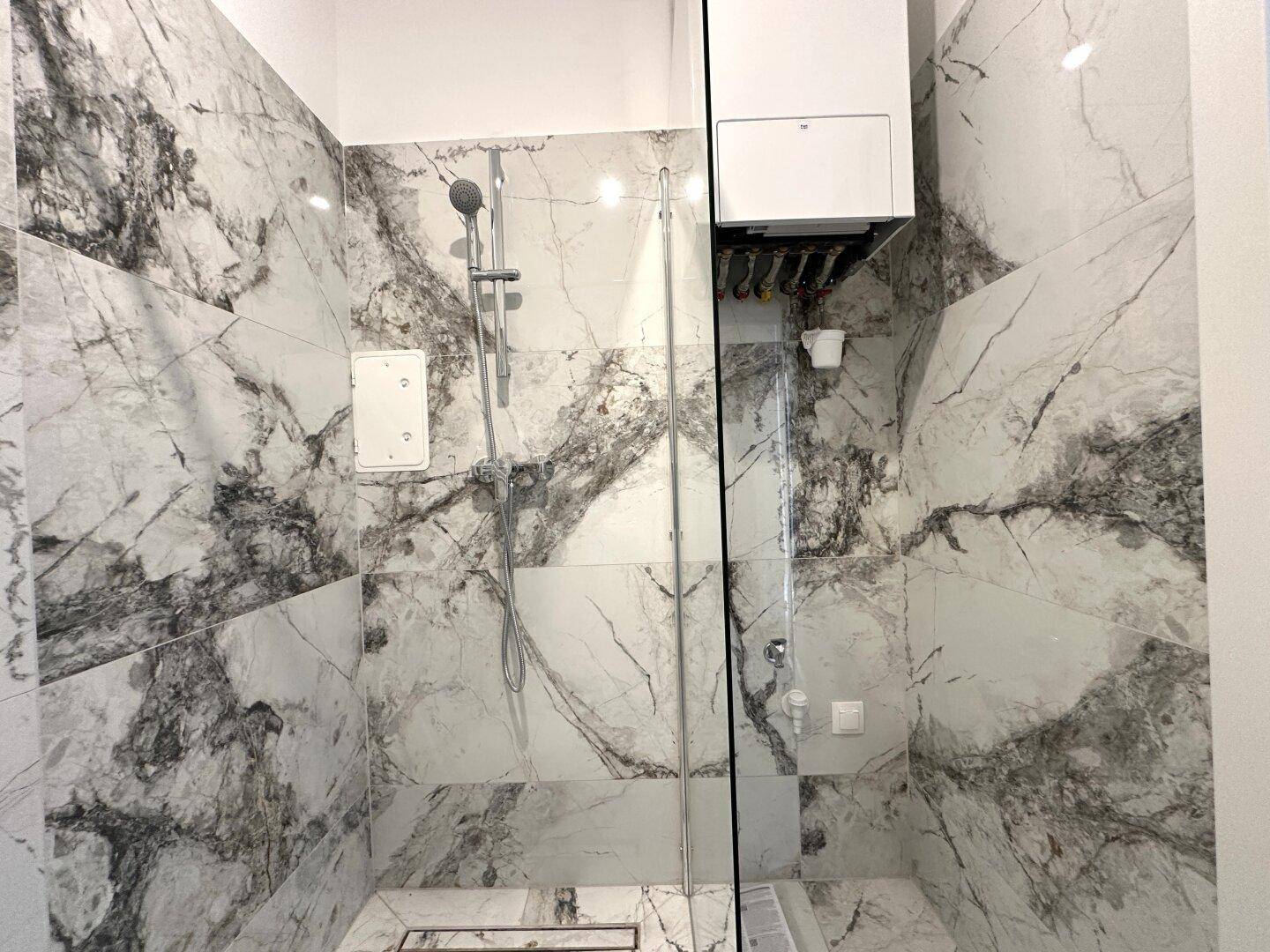 Geräumige, begehbare Dusche mit Glasabtrennung und luxuriösen Marmorfliesen im modernen Badezimmer.