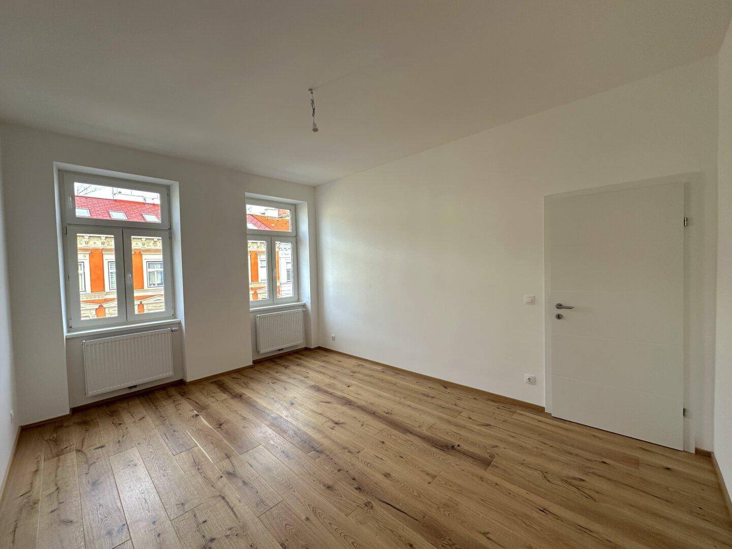 Heller Raum mit Holzboden und weiß gestrichenen Wänden, mit einer modernen Tür.