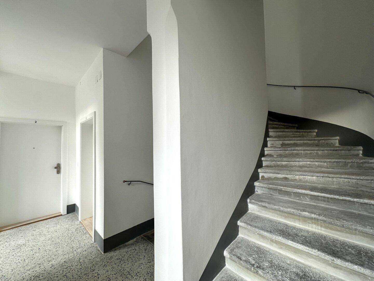 Treppenhaus mit Steinstufen und Handlauf, das zu den verschiedenen Etagen des Gebäudes führt.