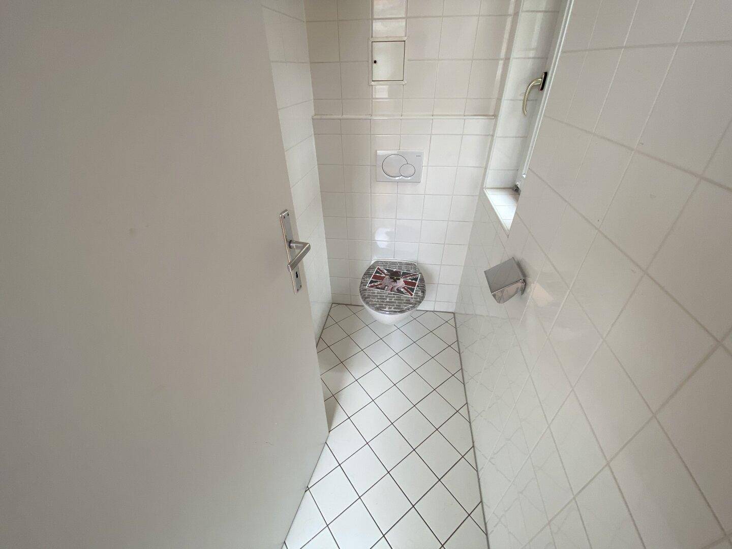 Kleines WC mit weißen Fliesen, Wand-WC und einer schlichten Einrichtung, sehr gepflegt.
