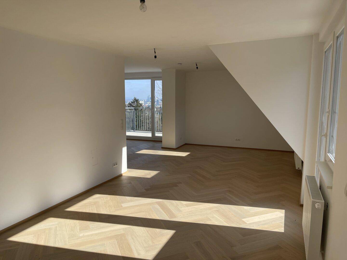 Geräumiges Zimmer mit Fischgrätparkett, viel Sonnenlicht und Blick ins Grüne.
