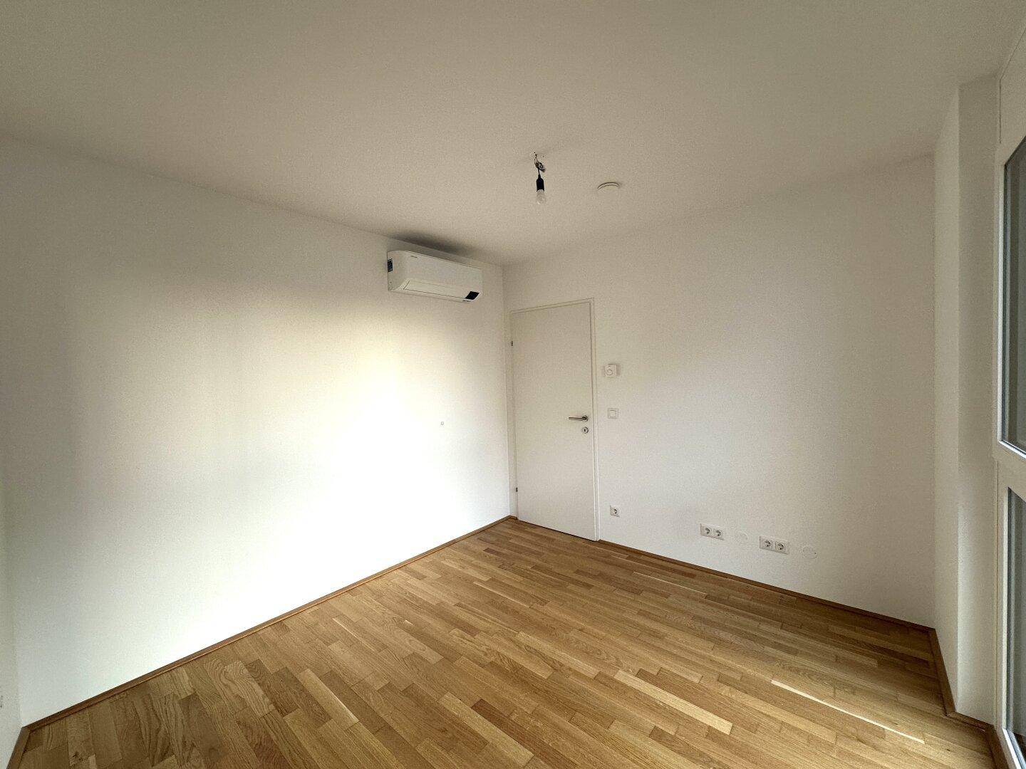 Helles Zimmer mit Holzboden und Klimaanlage, ideal als Schlaf- oder Arbeitszimmer nutzbar.