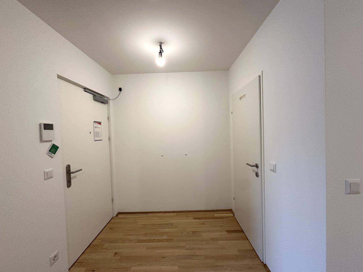 Eingangsbereich mit hellem Parkettboden und weißen Türen, der zu den weiteren Räumen führt.