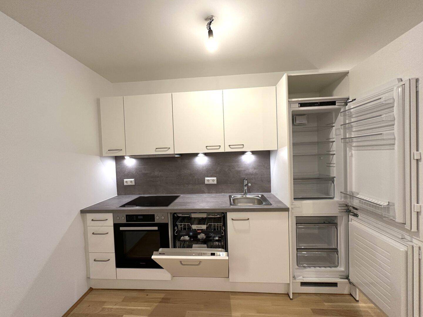 Voll ausgestattete Küche mit integriertem Geschirrspüler und Kühlschrank, bereit zur Nutzung.