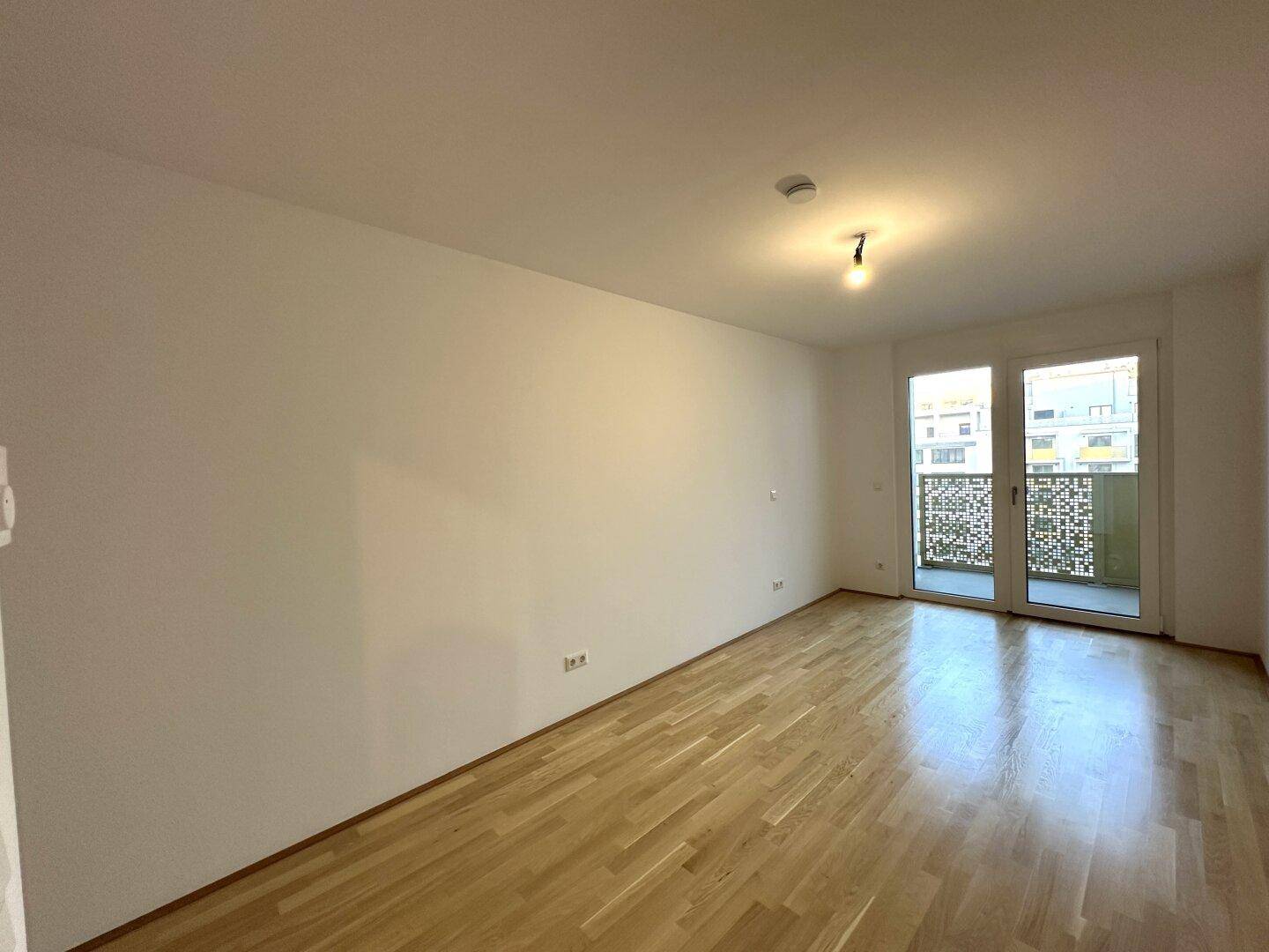 Lichtdurchflutetes Zimmer mit Parkettboden und Balkontür, bietet einen angenehmen Wohnkomfort.