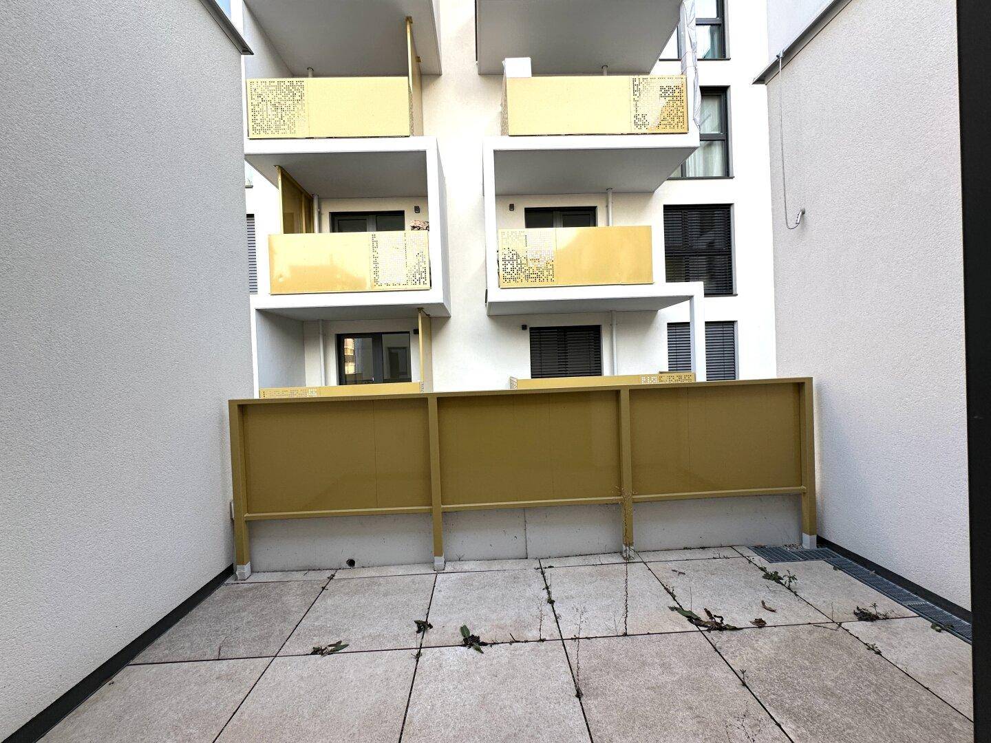 Kleine, geflieste Terrasse im Innenhofbereich, umgeben von Gebäudefassaden.