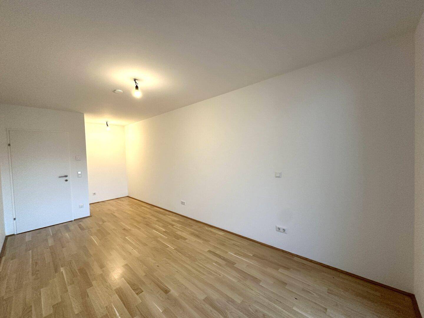Helles Schlafzimmer mit Holzboden und weißer Tür, bereit zur Möblierung.