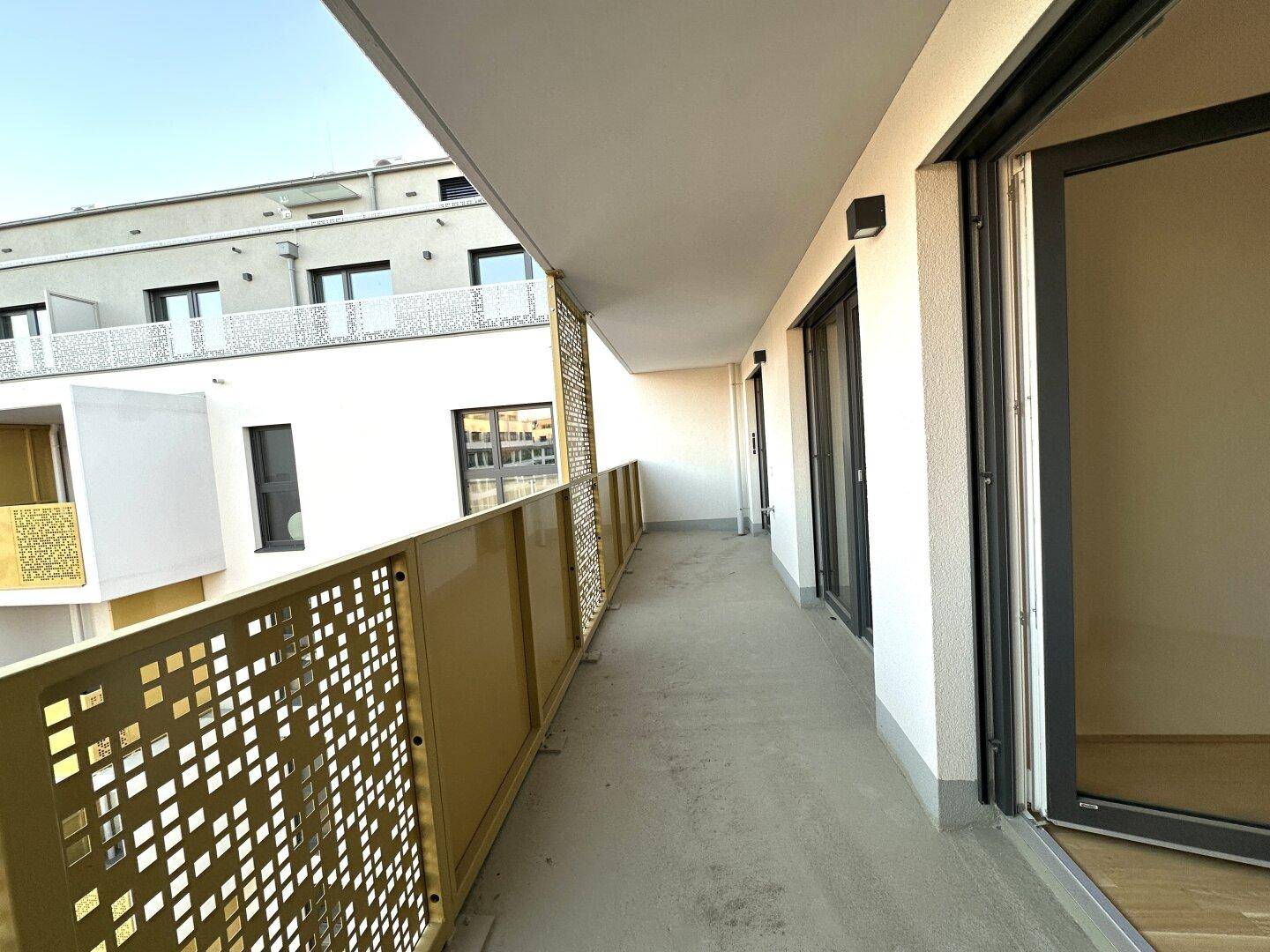 Langer Balkon mit modernem Geländer und Zugang von mehreren Zimmern.