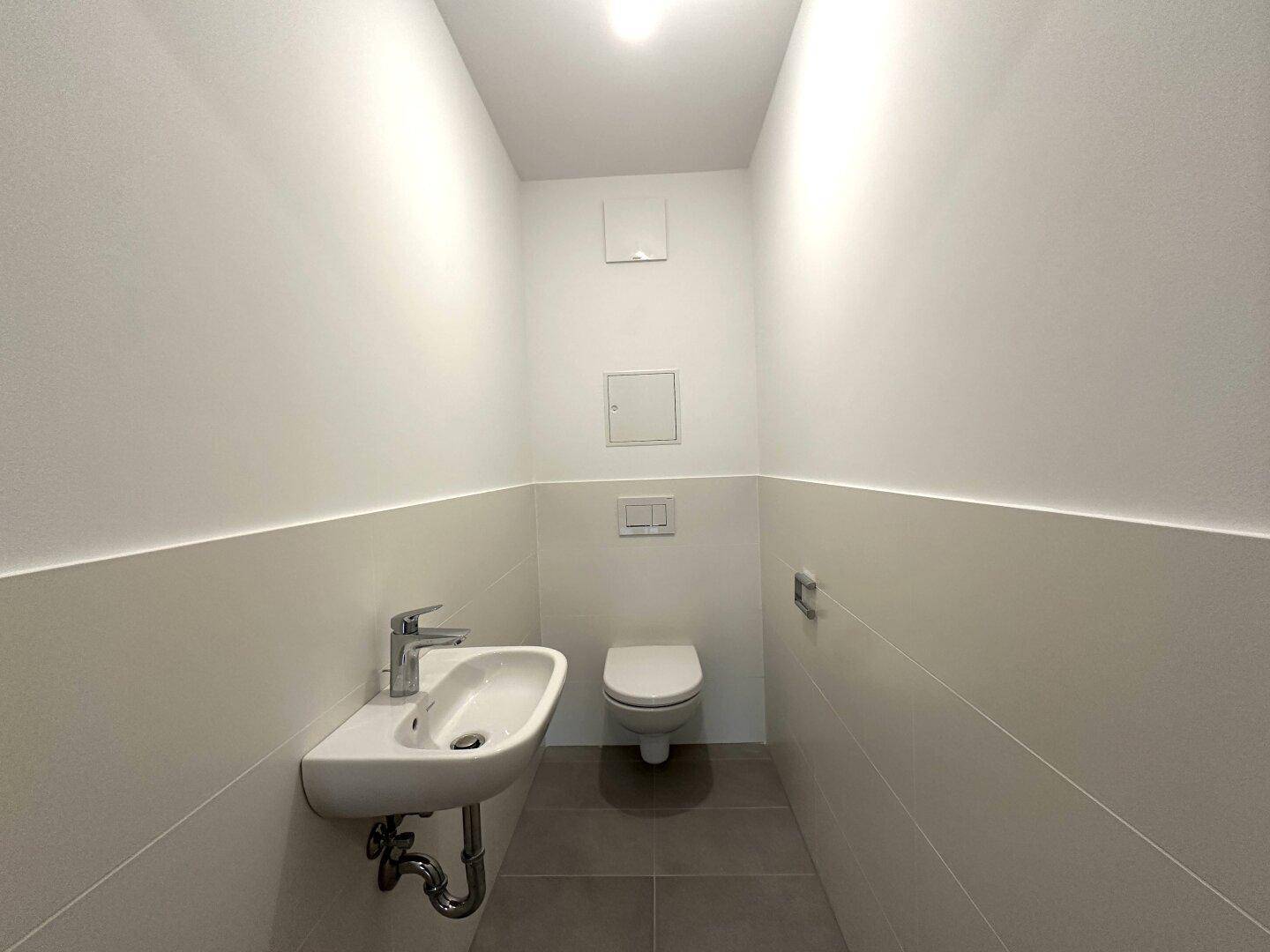 Separates Gäste-WC mit kleinem Waschbecken und wandhängender Toilette.