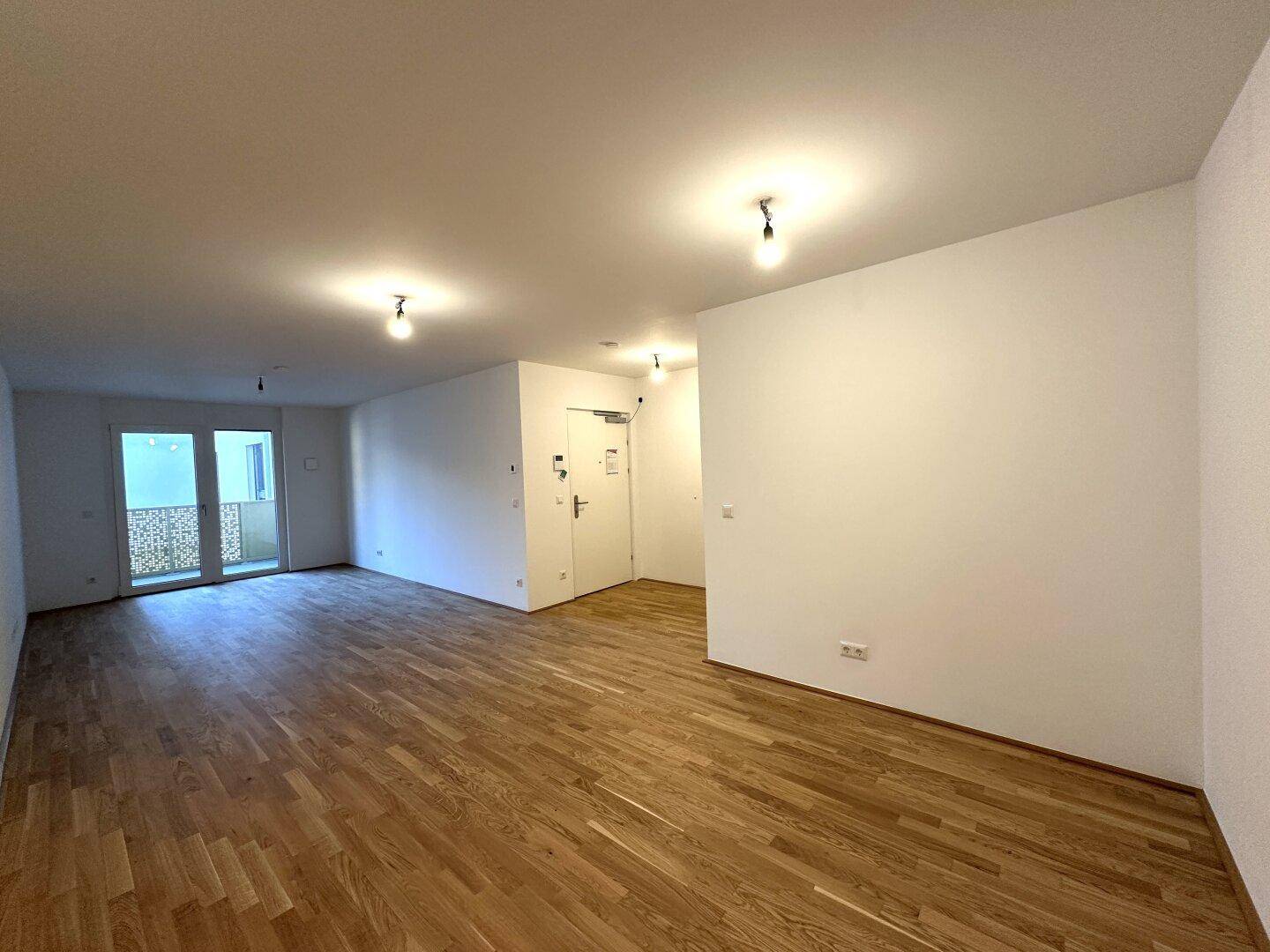 Weitläufiger Wohnbereich mit Parkettboden und Zugang zum Eingangsbereich der Wohnung.