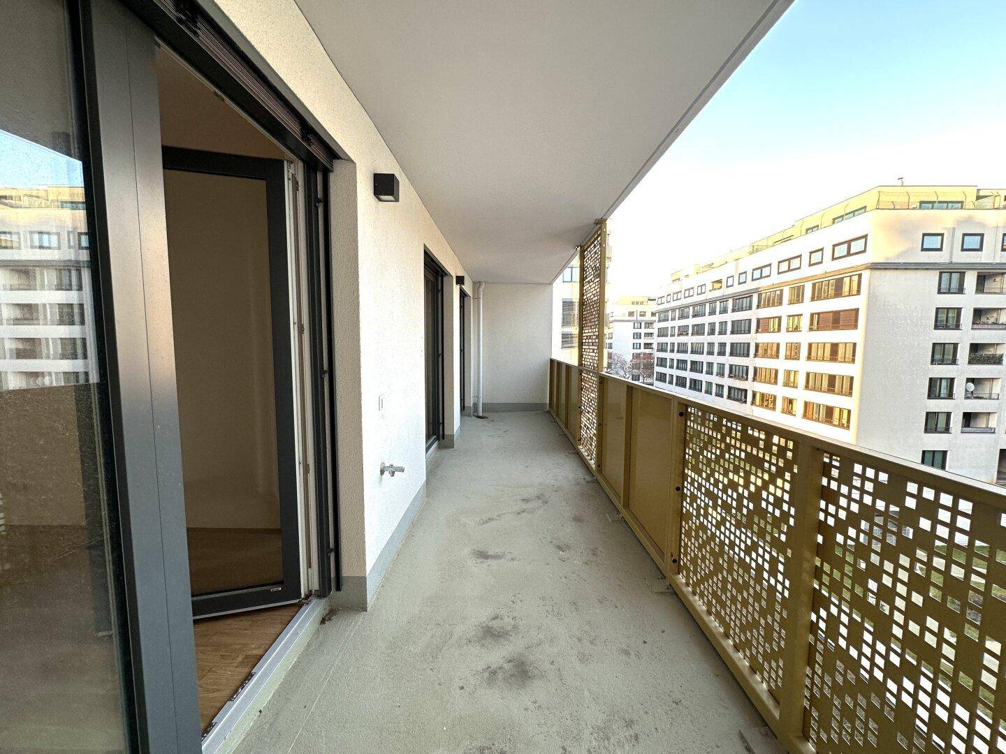 Langer Balkon mit modernem goldfarbenem Geländer und Blick auf umliegende Gebäude.
