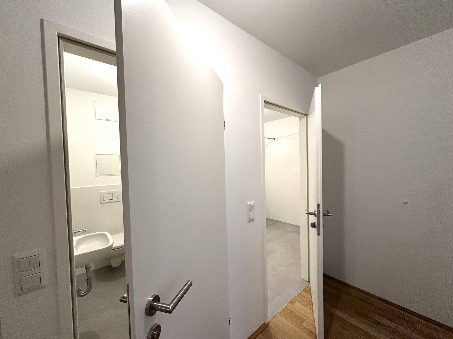 Heller Flur mit Parkettboden und Zugang zu einem Gäste-WC und einem weiteren Raum.