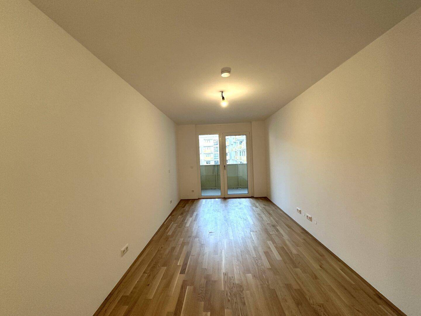 Geräumiges Zimmer mit Parkettboden und Balkonzugang, ideal für vielfältige Nutzung.