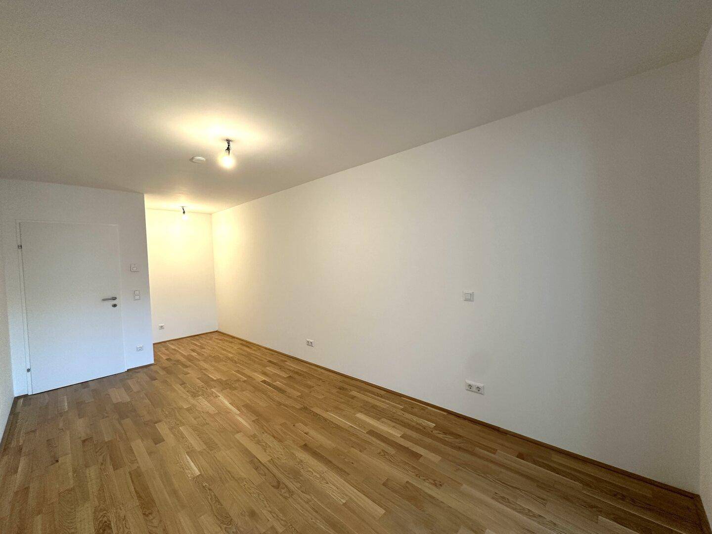 Heller Raum mit Parkettboden und weiß gestrichenen Wänden, bietet viel Gestaltungspotenzial.