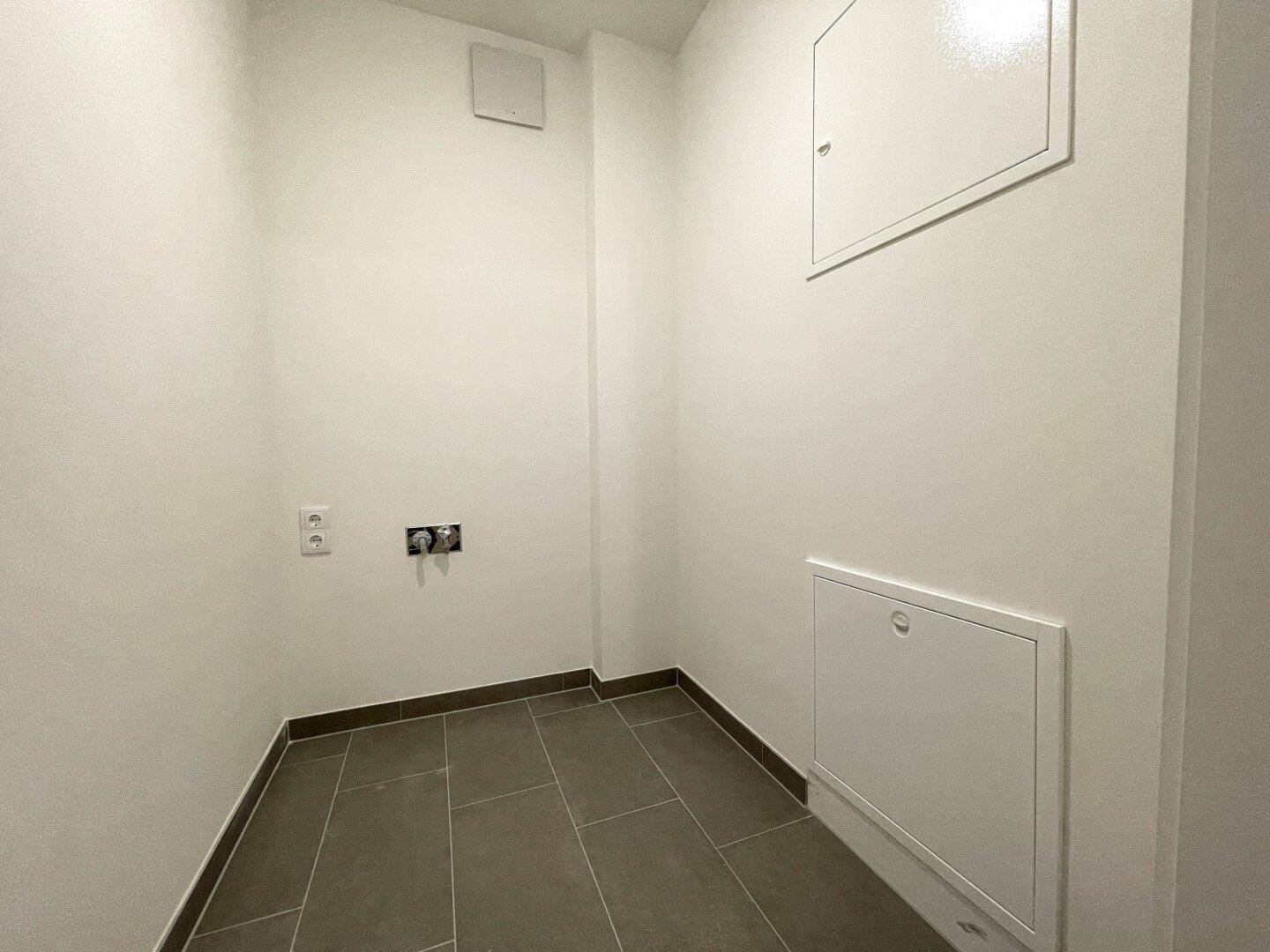 Kleiner Hauswirtschaftsraum mit Fliesenboden und Anschlüssen für Waschmaschine.