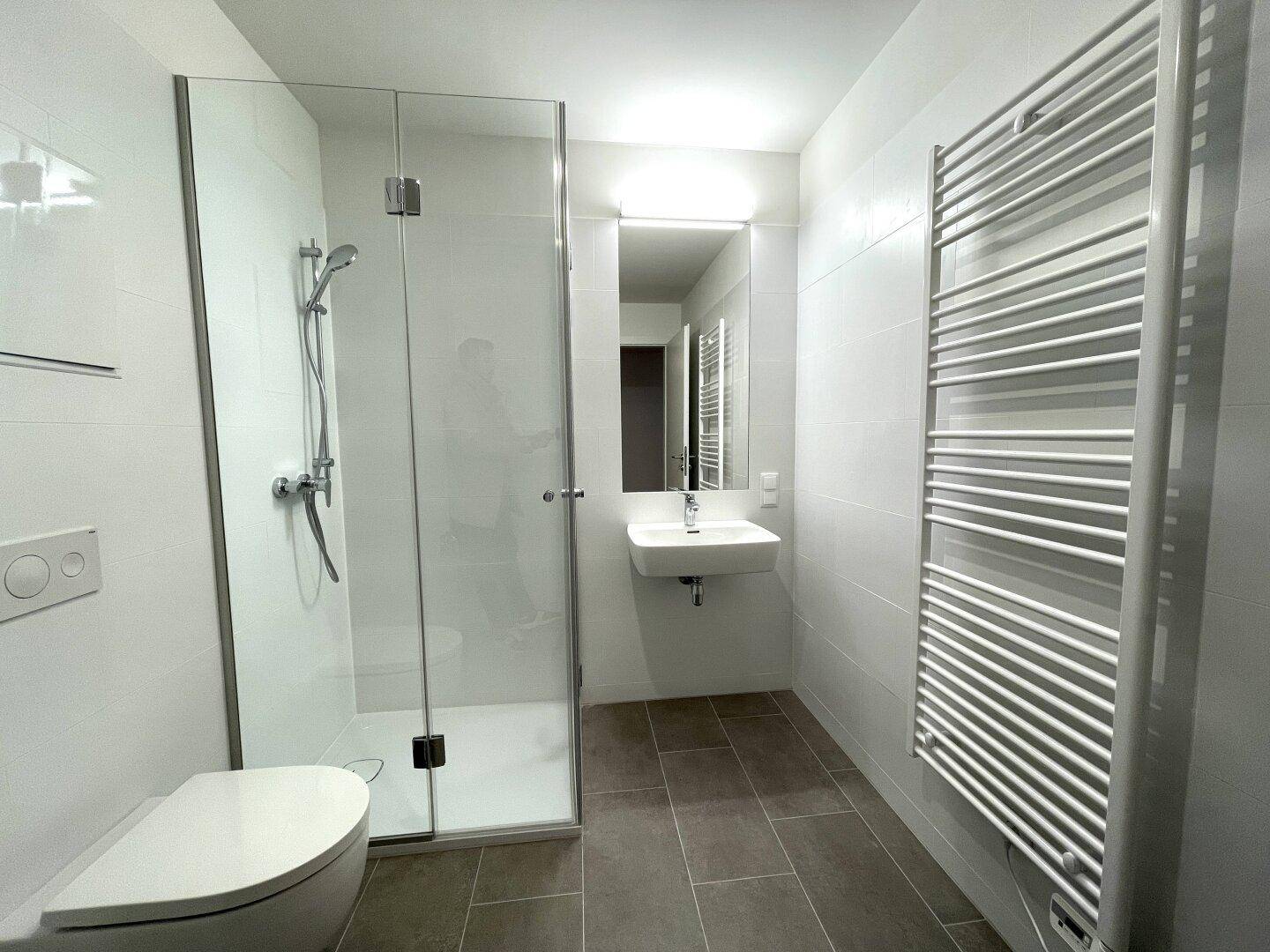 Helles Badezimmer mit großer Duschkabine, Waschbecken und modernem Design.
