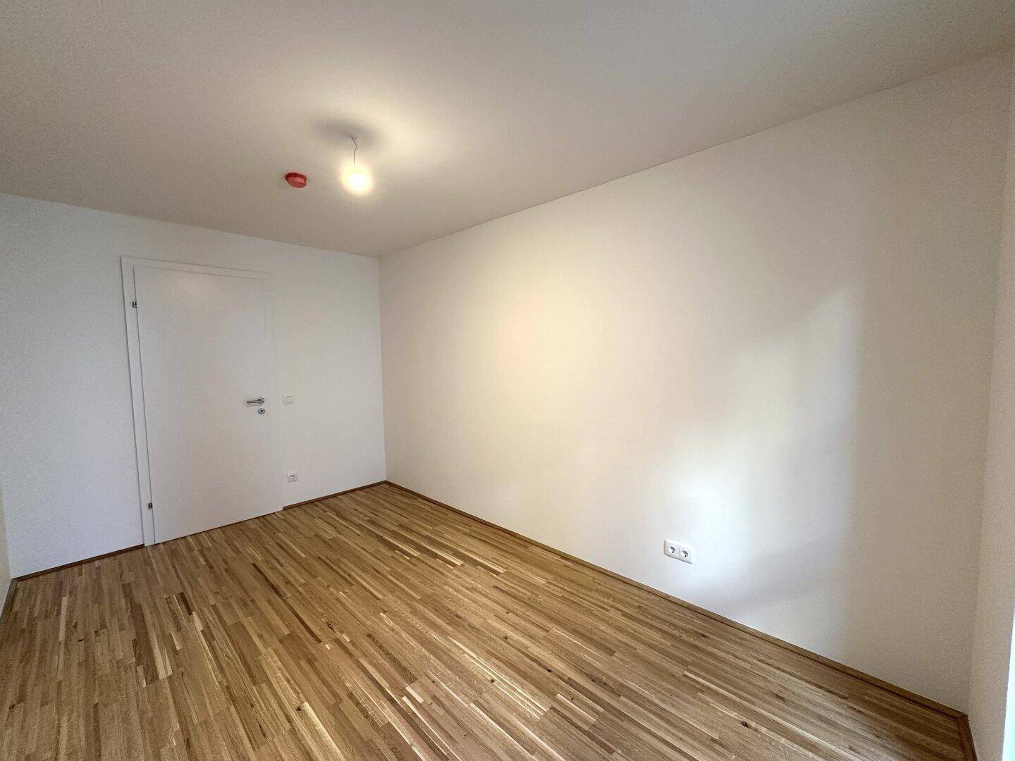 Geräumiges Zimmer mit Parkettboden und weiß gestrichenen Wänden, bereit für individuelle Gestaltung.