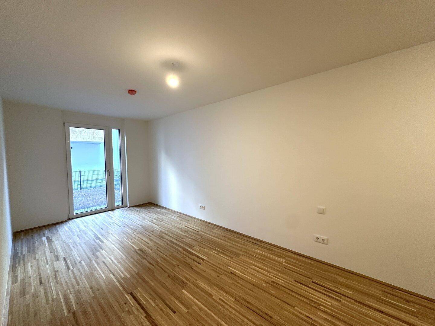Helles Zimmer mit Parkettboden und Zugang zu einem Außenbereich, ideal für frische Luft und Tageslicht.