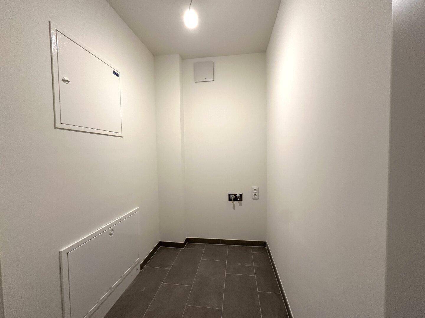 Praktischer Hauswirtschaftsraum mit Fliesenboden und Anschlüssen für Waschmaschine und Trockner.