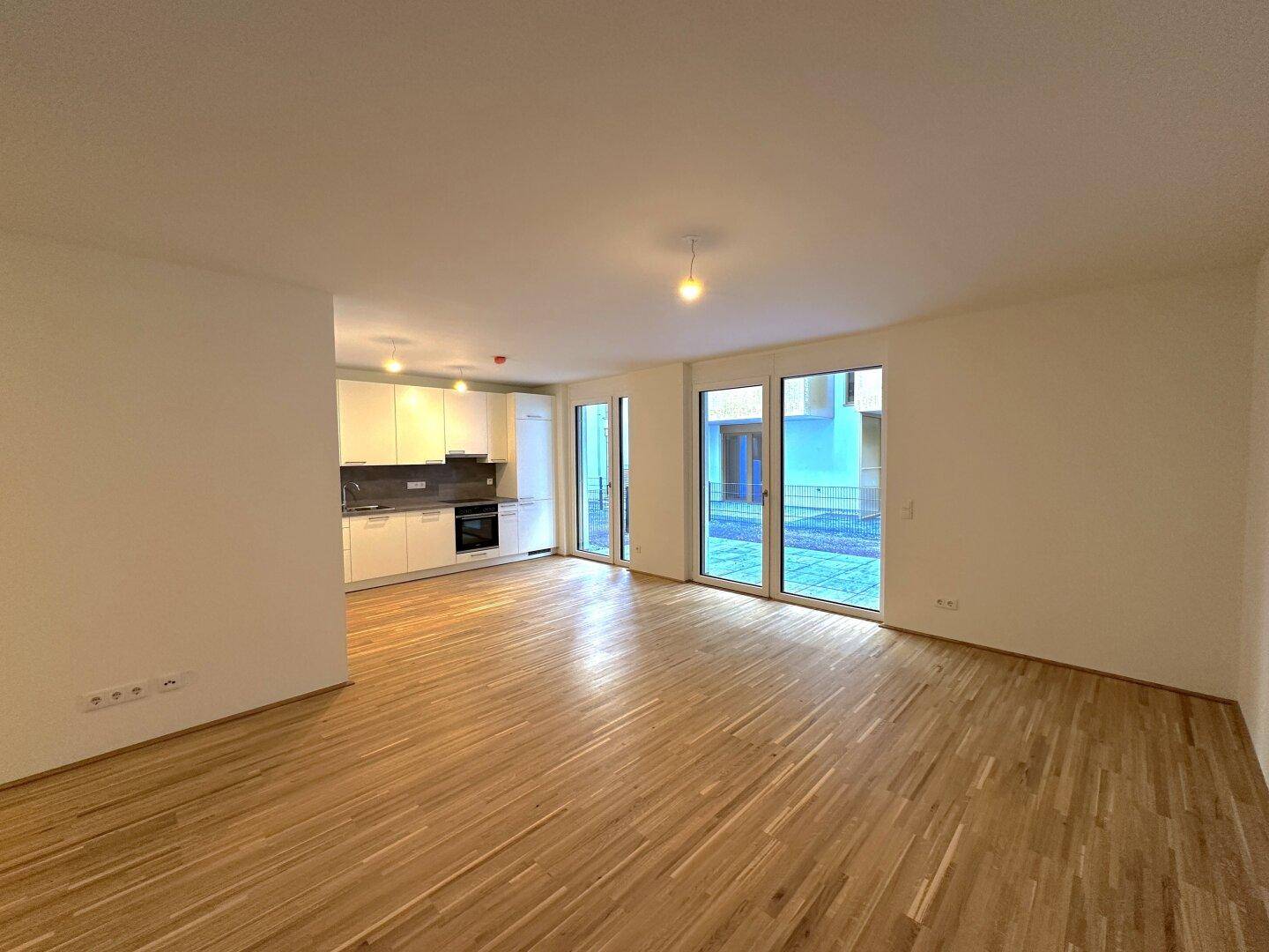 Offener Wohn- und Essbereich mit integrierter Küche und viel Tageslicht durch die großen Fensterfronten.