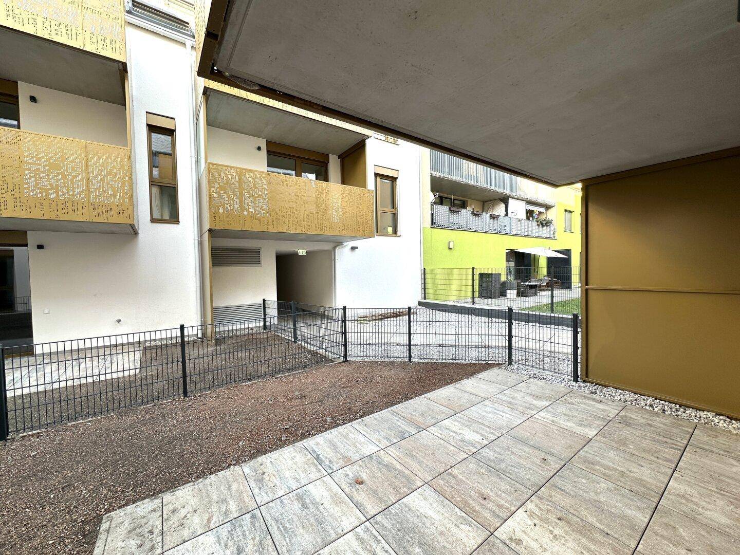 Geräumige Terrasse mit Fliesenboden und Blick auf die moderne Architektur des Wohnkomplexes.