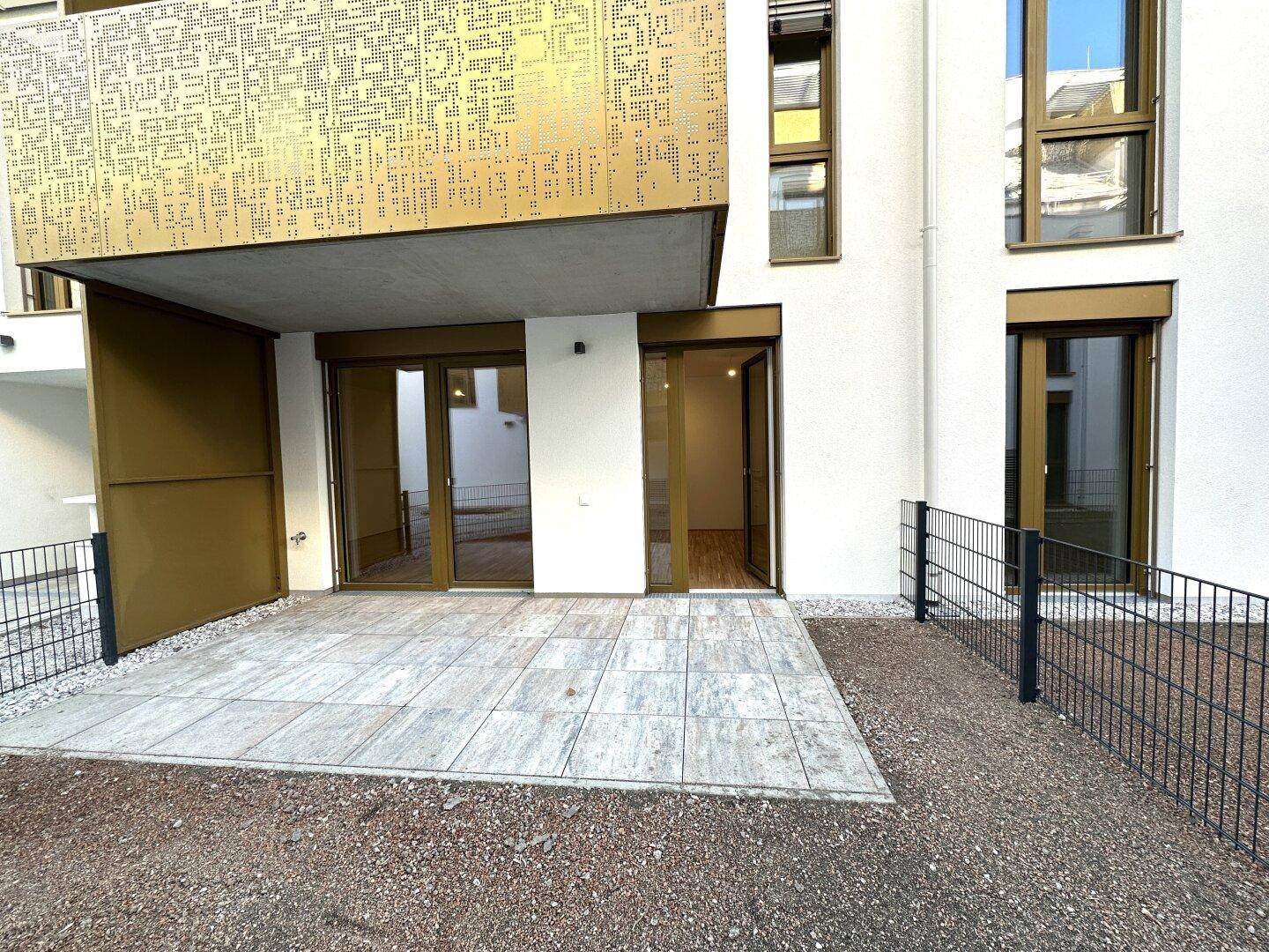 Großzügige Terrasse mit direktem Zugang zum Wohnbereich durch breite Glastüren, ideal für Entspannung.