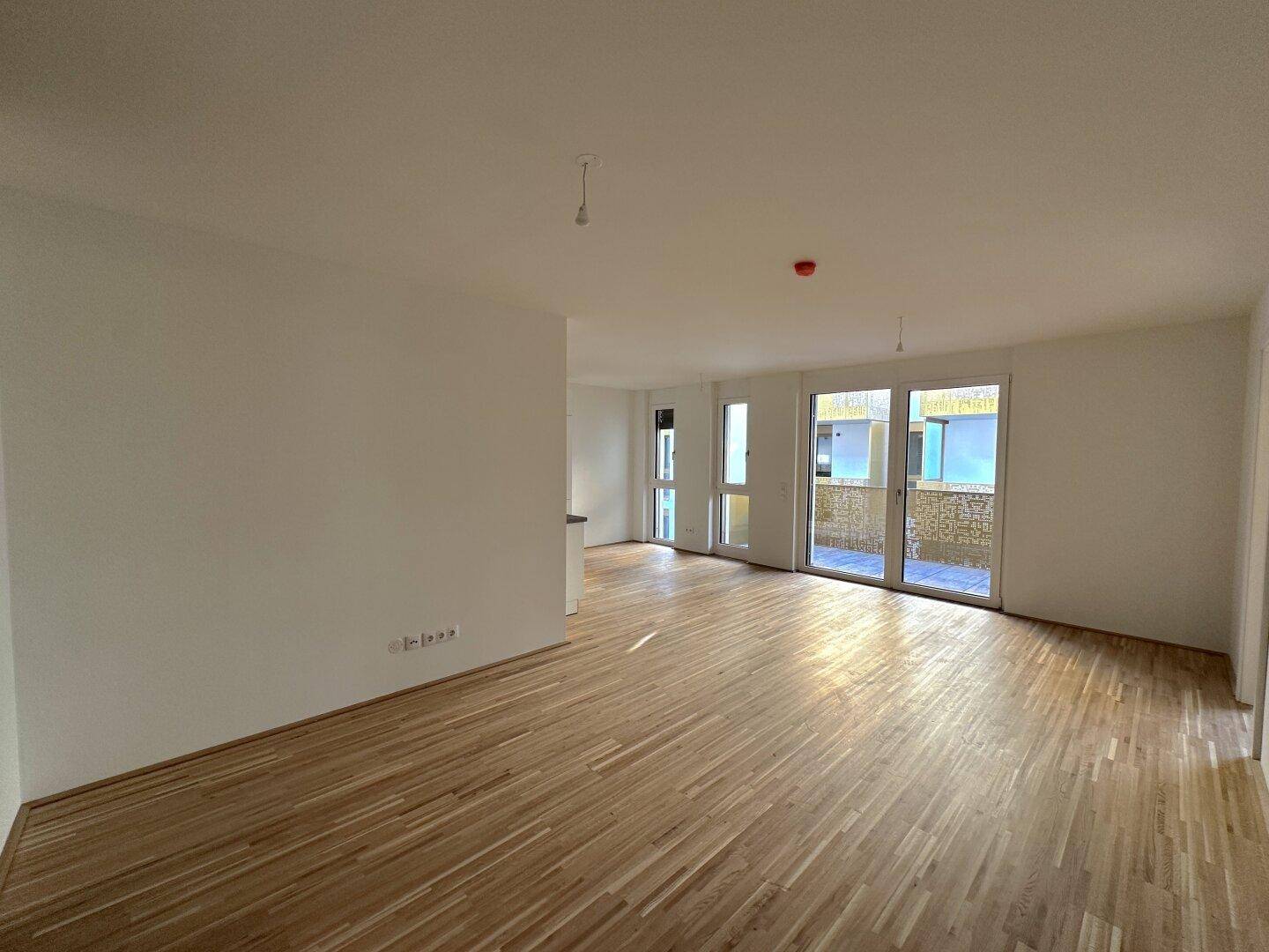 Heller Wohn- und Essbereich mit Parkettboden und direktem Zugang zum Balkon, der viel Licht spendet.