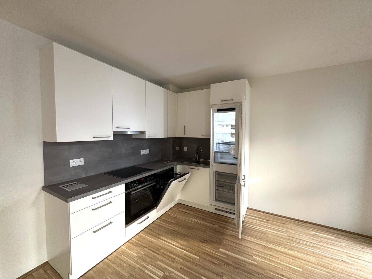 Voll ausgestattete moderne Küche mit integriertem Kühlschrank und Geschirrspüler, bereit zur Nutzung.