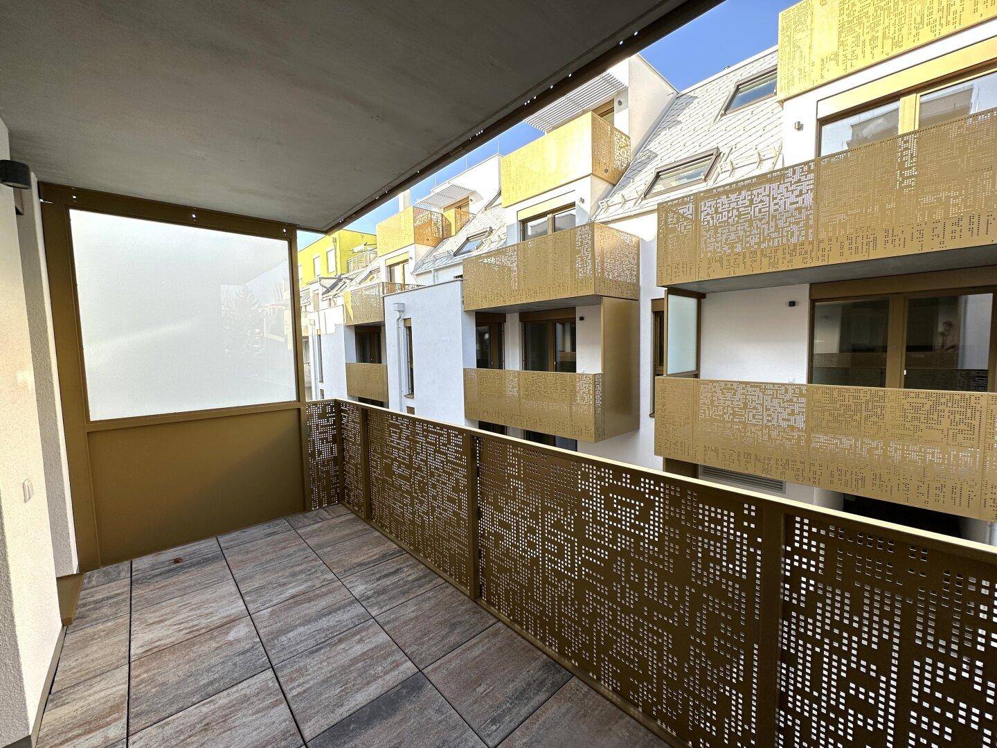 Moderner Balkon mit Fliesenboden und dekorativem Metallgeländer, bietet einen Blick auf die umliegenden Gebäude.